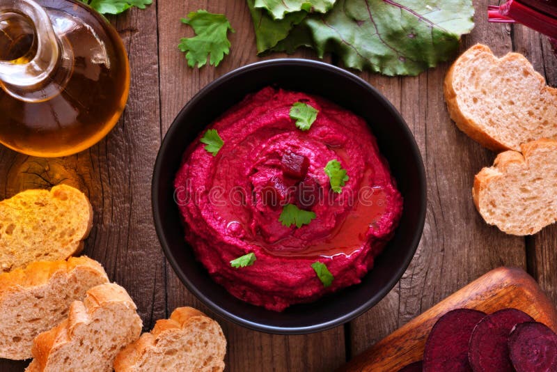 Εμβύθιση hummus τεύτλων, υπερυψωμένη επιτραπέζια σκηνή με το ψωμί και συστατικά στο ξύλο στοκ φωτογραφίες