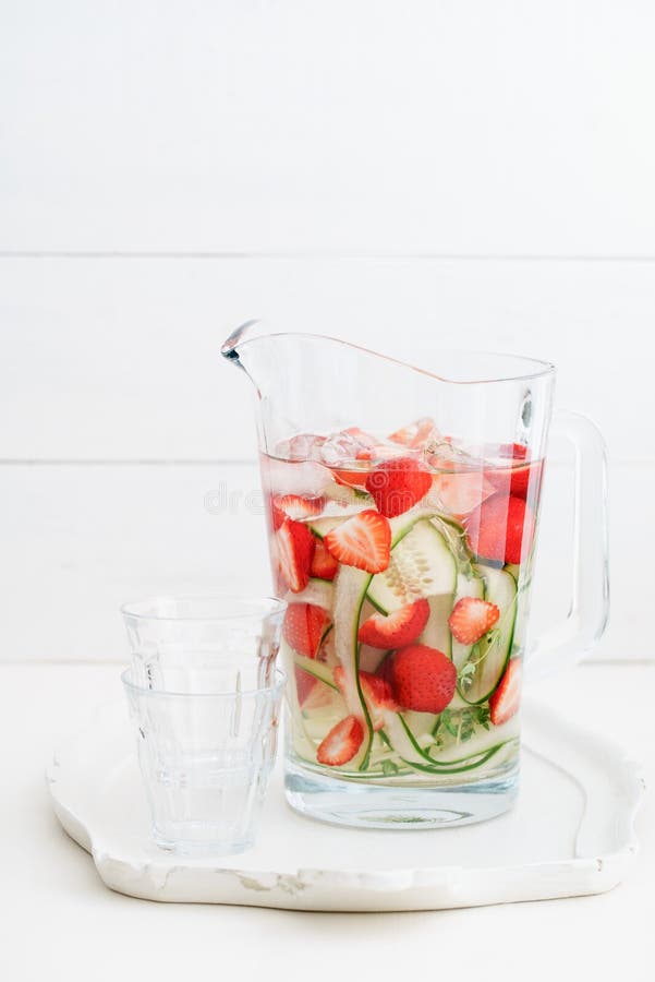 Infused water with cucumber, strawberries and thyme in a pitcher. Infused water with cucumber, strawberries and thyme in a pitcher