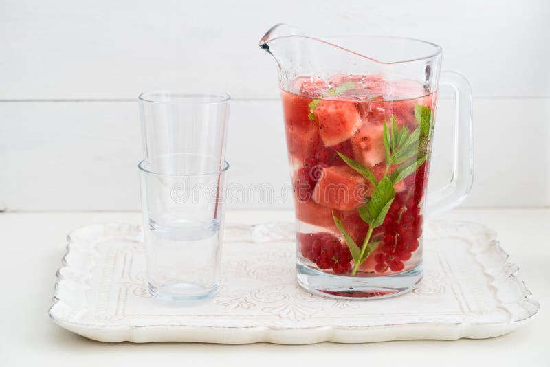Infused water with watermelons, red currants and mint in a pitcher. Infused water with watermelons, red currants and mint in a pitcher