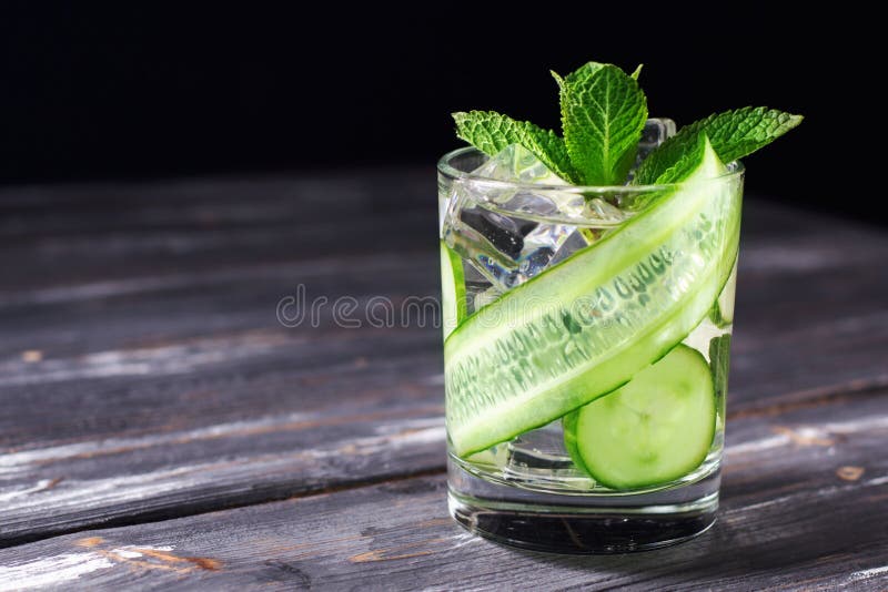 Infused cucumber drink with mint. Detox water. Darck background. Infused cucumber drink with mint. Detox water. Darck background