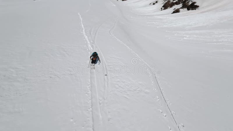 εναέρια πανοραμική προβολή αθλητές σκι αναρρίχηση χιονισμένο βουνό κορυφή ηλιόλουστο αλπικό χειμερινό τοπίο
