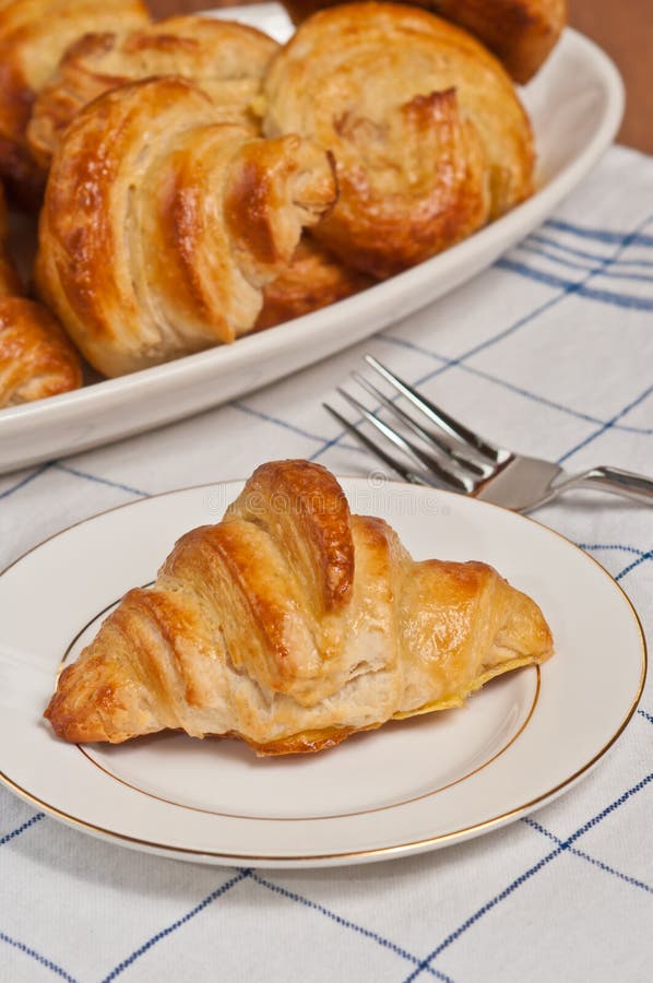 Ενιαίος πρόσφατα ψημένος, σπιτικός croissant σε ένα στρογγυλό, άσπρο πιάτο στοκ εικόνες Ενιαίος πρόσφατα ψημένος, σπιτικός croissant σε ένα στρογγυλό, άσπρο πιάτο στοκ εικόνες