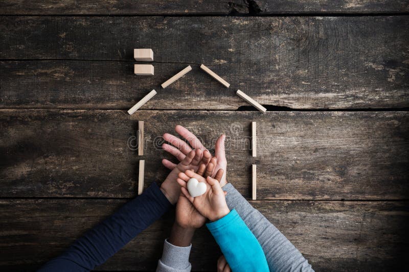 Top view of a family of four placing hands one on top of the other in a conceptual image of love, togetherness and safety. Top view of a family of four placing hands one on top of the other in a conceptual image of love, togetherness and safety