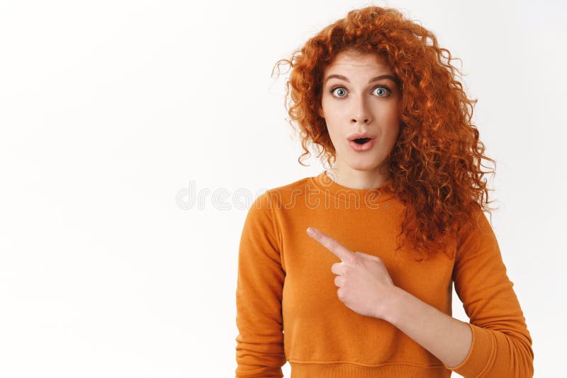 Εντυπωσιακή όμορφη, με κουρέλια κοκκινομάλλα, γυναίκα που δείχνει αριστερά, να βλέπει εκπληκτικά αντίγραφα χώρου και να δείχνει σ στοκ εικόνες με δικαίωμα ελεύθερης χρήσης