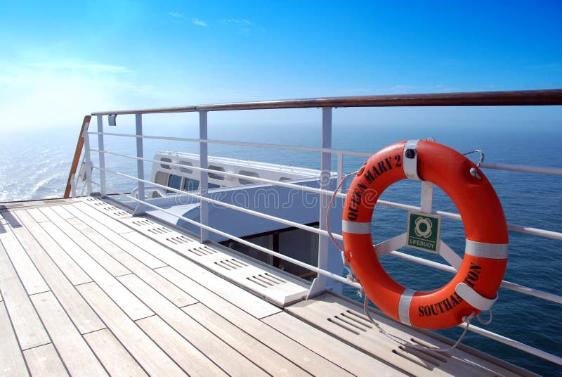 Orange lifebelt and teak deck under an azure blue sky aboard ocean liner Queen Mary 2. Orange lifebelt and teak deck under an azure blue sky aboard ocean liner Queen Mary 2