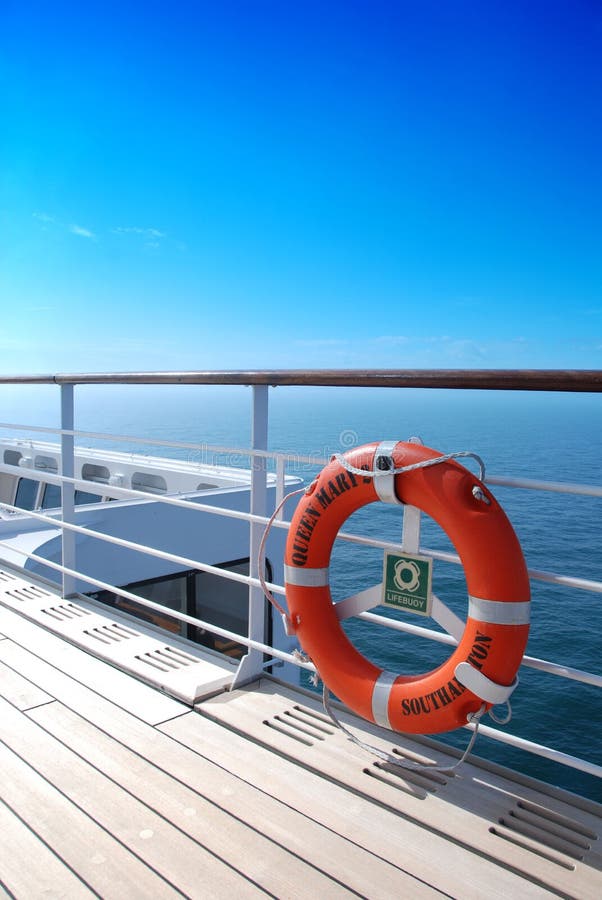 Orange lifebelt and teak deck under an azure blue sky aboard ocean liner Queen Mary 2. Orange lifebelt and teak deck under an azure blue sky aboard ocean liner Queen Mary 2