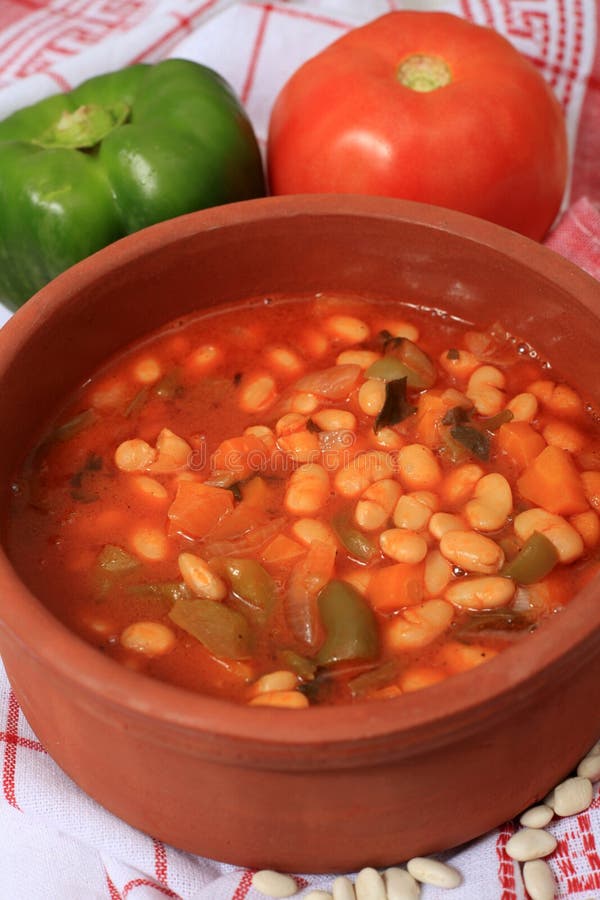 A terracotta serving bowl of traditional Greek white bean soup. with tomato and capsicum and dried white beans, which are among the main ingredients, along with olive oil, celery, carrot and onion. A terracotta serving bowl of traditional Greek white bean soup. with tomato and capsicum and dried white beans, which are among the main ingredients, along with olive oil, celery, carrot and onion.