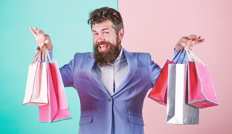 Επίσημο κοστούμι επιχειρηματιών hipster ατόμων το γενειοφόρο φέρνει τις τσάντες αγορών εγγράφου Έτοιμος για τις διακοπές Αγοράστε στοκ φωτογραφία με δικαίωμα ελεύθερης χρήσης