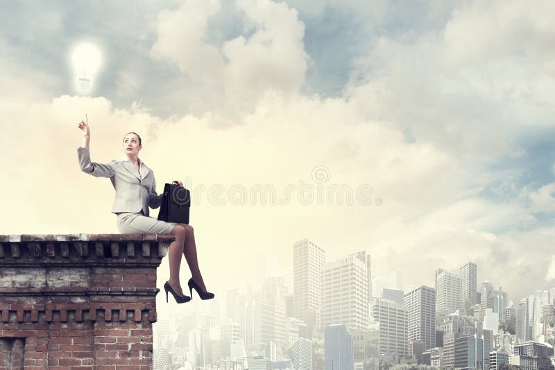 Fearless businesswoman with suitcase sitting on building top. Fearless businesswoman with suitcase sitting on building top