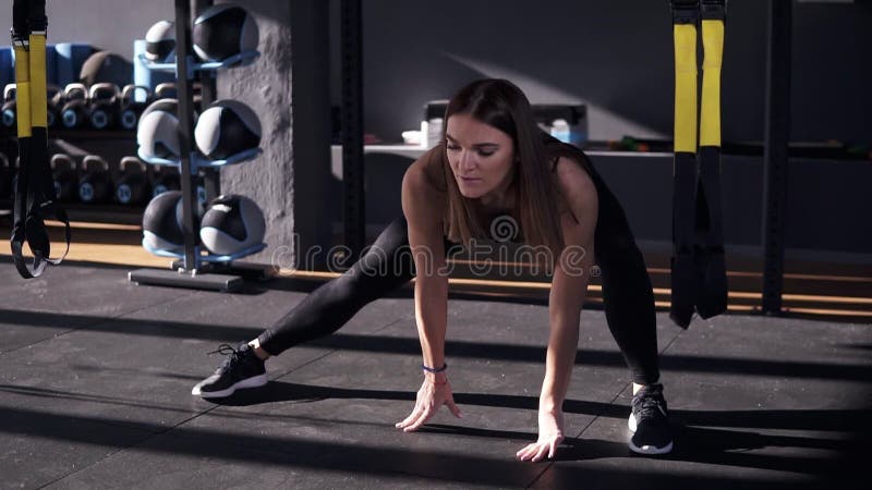 Επαγγελματίας στον αθλητισμό Μπροστινή άποψη της όμορφης νέας γυναίκας sportswear που κάνει το τέντωμα ενώ στο πάτωμα σε ένα σκοτ