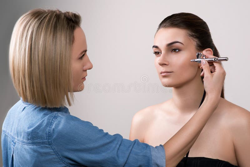 Επαγγελματικό visagist που κάνει makeup και που χρησιμοποιεί airbrush Κορίτσι που κάνει makeup στο σαλόνι ομορφιάς Πρότυπο brunet στοκ εικόνα Επαγγελματικό visagist που κάνει makeup και που χρησιμοποιεί airbrush Κορίτσι που κάνει makeup στο σαλόνι ομορφιάς Πρότυπο brunet στοκ εικόνα