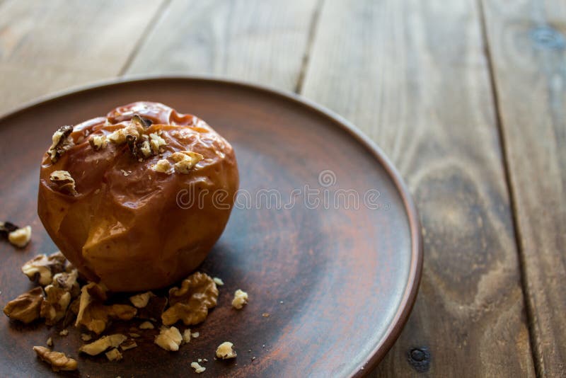 A dessert with baked apple and nuts on a clay plate. A dessert with baked apple and nuts on a clay plate