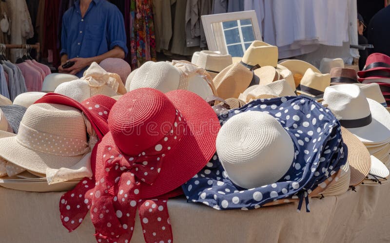Selection of woman`s summer hats together with some men`s hats seen at market stall in a famous market. The background shows a mirror for trying the hats on. Selection of woman`s summer hats together with some men`s hats seen at market stall in a famous market. The background shows a mirror for trying the hats on.