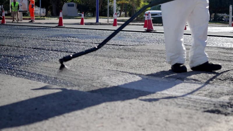 επισκευή δρόμων στην πόλη κοντά στα πόδια ενός εργαζομένου με λευκό κοστούμι που κάνει τη δουλειά του απόθεμα βίντεο
