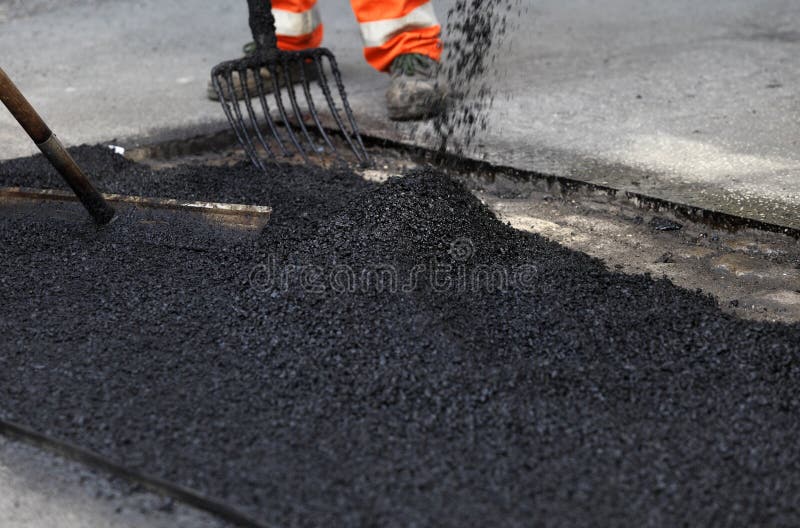 Asphalt patch being smoothed to repair pavement on a street or roadway. Asphalt patch being smoothed to repair pavement on a street or roadway.