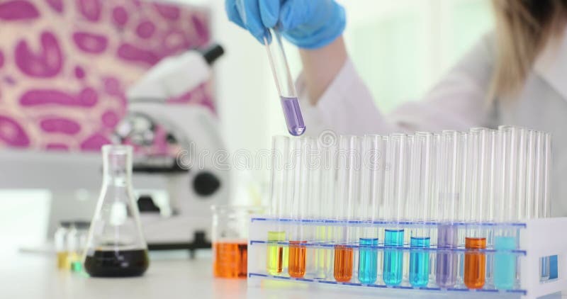 επιστήμονας σε γάντια παίρνει δοκιμαστικό σωλήνα με υγρό από το rack απόθεμα βίντεο