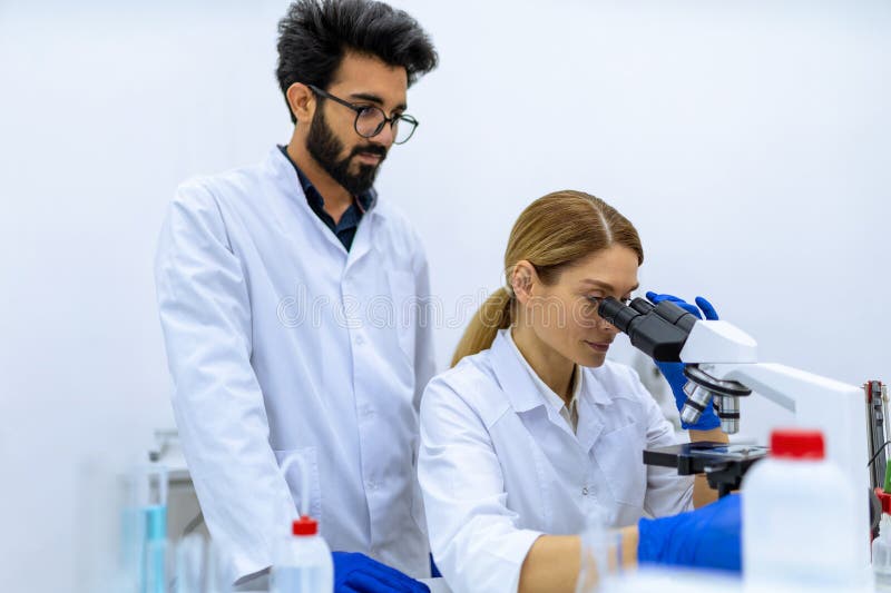 επιστήμονες που χρησιμοποιούν μικροσκόπιο για ανάλυση δειγμάτων, ομάδα ειδικών που εργάζονται σε εργαστήρια. στοκ εικόνα