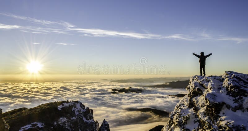 Hiker is enjoying the success of the climb in a majestic sunrise. Hiker is enjoying the success of the climb in a majestic sunrise