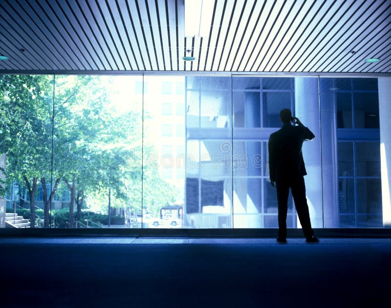 Businessman communicating standing on the phone in front of a row of windows. Businessman communicating standing on the phone in front of a row of windows