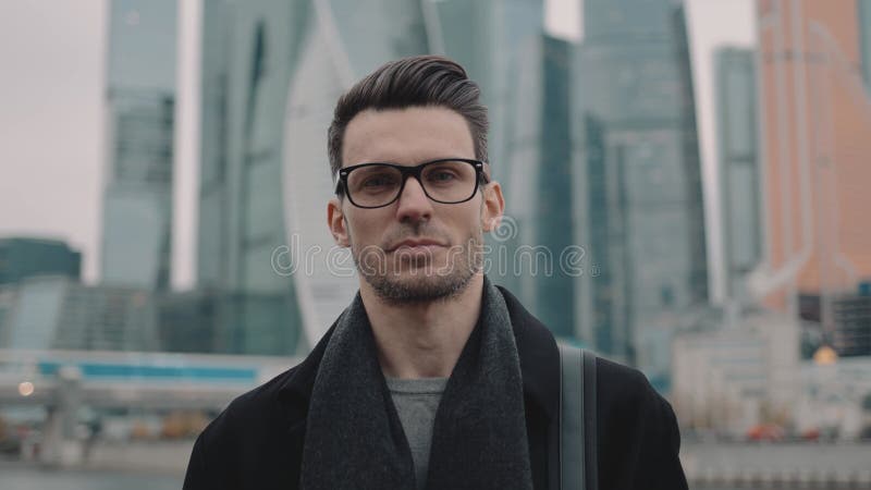 επιχειρηματίας με παλτό και γυαλιά στο φόντο του κέντρου επιχειρήσεων ουρανοξύστη