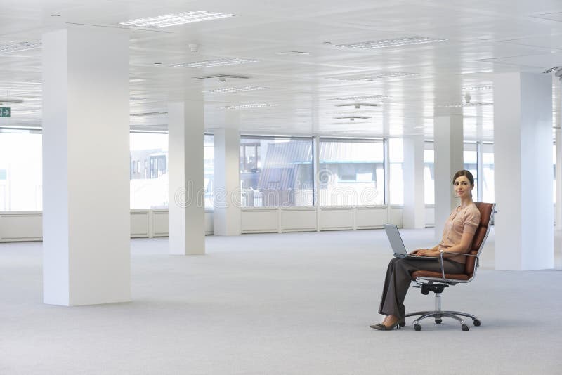 Επιχειρηματίας που χρησιμοποιεί το lap-top στην έδρα στην αρχή στοκ φωτογραφίες