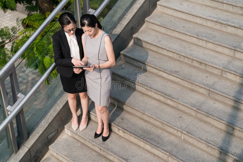 Επιχειρηματίες που στέκονται στα σκαλοπάτια που χρησιμοποιούν μια ταμπλέτα στοκ εικόνες Επιχειρηματίες που στέκονται στα σκαλοπάτια που χρησιμοποιούν μια ταμπλέτα στοκ εικόνες