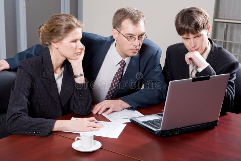 Business team of three professionals looking at monitor of laptop in the office. Business team of three professionals looking at monitor of laptop in the office