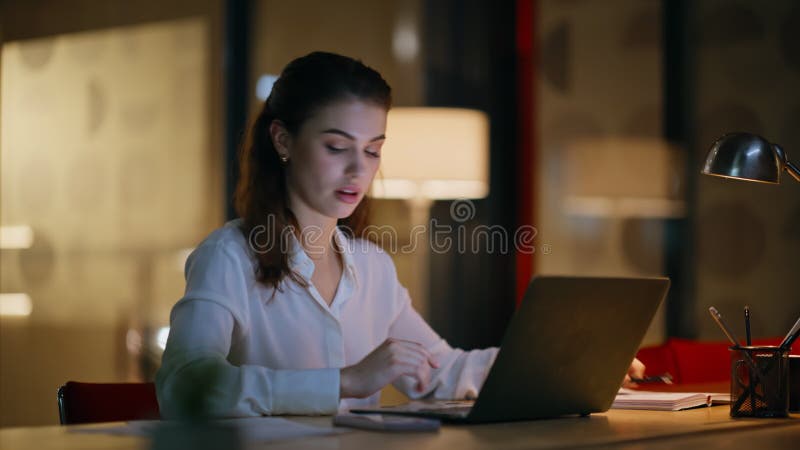 Εργαζόμενη γυναίκα που πληκτρολογεί φορητό υπολογιστή στο βραδινό γραφείο κλείνει. Σοβαρή επιχειρηματίας απόθεμα βίντεο