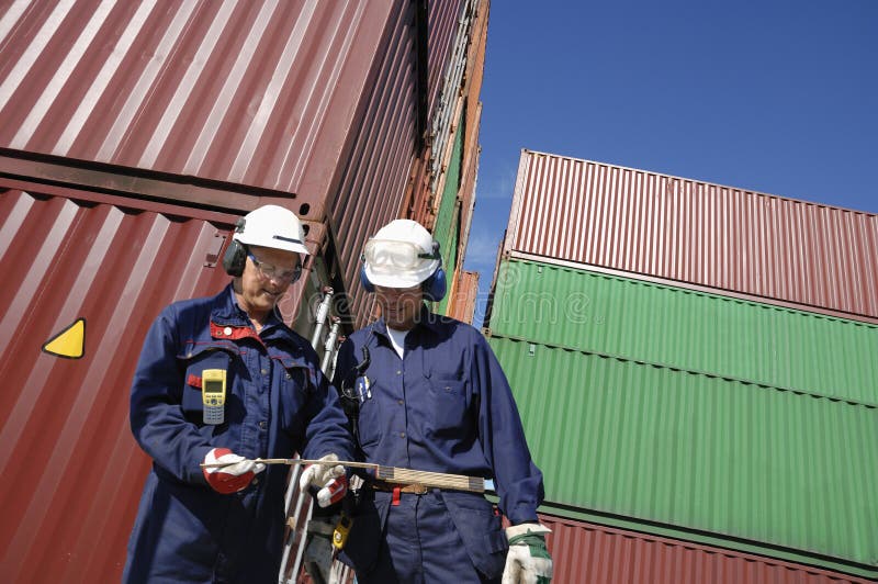 Workers with stacks of cargo containers in background. Workers with stacks of cargo containers in background.