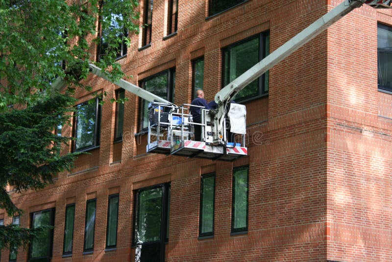 Workers in cherry picker inspecting window. Workers in cherry picker inspecting window