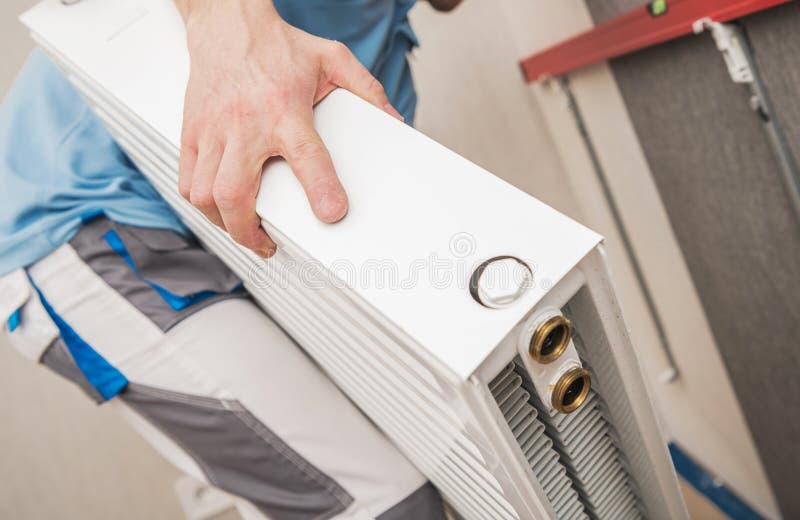 εργαζόμενος hvac που εγκαθιστά θερμαντικό ψυγείο για οικιακή θέρμανση στοκ εικόνα