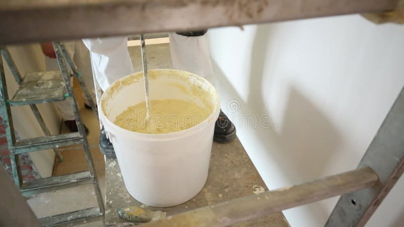 εργαζόμενος με λευκή στολή αναμιγνύει το stucco στο απόθεμα βίντεο