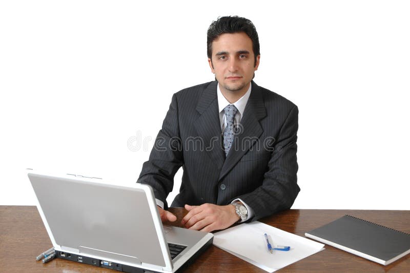 A middle eastern man works on his laptop at his desk. Man isolated on white background. Man with business suit and tie in an office setting. A middle eastern man works on his laptop at his desk. Man isolated on white background. Man with business suit and tie in an office setting.