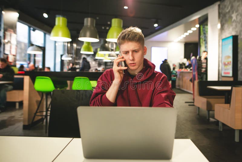Εργασίες Freelancer για ένα lap-top σε έναν καφέ και τις κλήσεις το τηλέφωνο Συνεδρίαση επιχειρησιακών νεαρών άνδρων με ένα lap-t στοκ εικόνες Εργασίες Freelancer για ένα lap-top σε έναν καφέ και τις κλήσεις το τηλέφωνο Συνεδρίαση επιχειρησιακών νεαρών άνδρων με ένα lap-t στοκ εικόνες