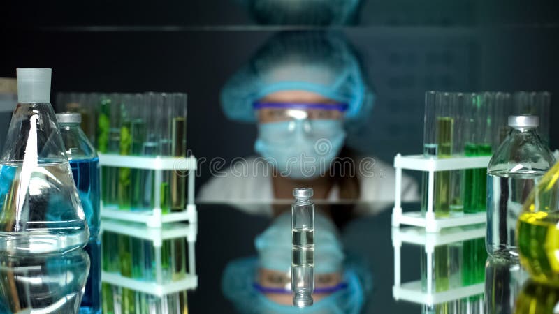 Εργαστηριακός βοηθός που εξετάζει το μπουκάλι με το διαφανές υγρό, ανάλυση εμβολίων στοκ φωτογραφία με δικαίωμα ελεύθερης χρήσης Εργαστηριακός βοηθός που εξετάζει το μπουκάλι με το διαφανές υγρό, ανάλυση εμβολίων στοκ φωτογραφία με δικαίωμα ελεύθερης χρήσης