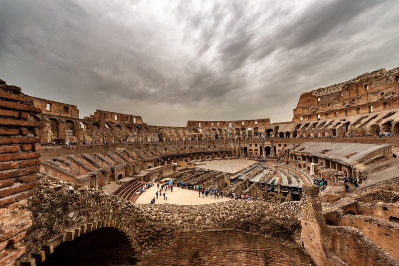 Interior of the Colosseum of Rome Amphitheatrum Flavium 72 a.D with many tourists on a cloudy day. UNESCO world heritage site. Latium, Italy, Europe. Interior of the Colosseum of Rome Amphitheatrum Flavium 72 a.D with many tourists on a cloudy day. UNESCO world heritage site. Latium, Italy, Europe