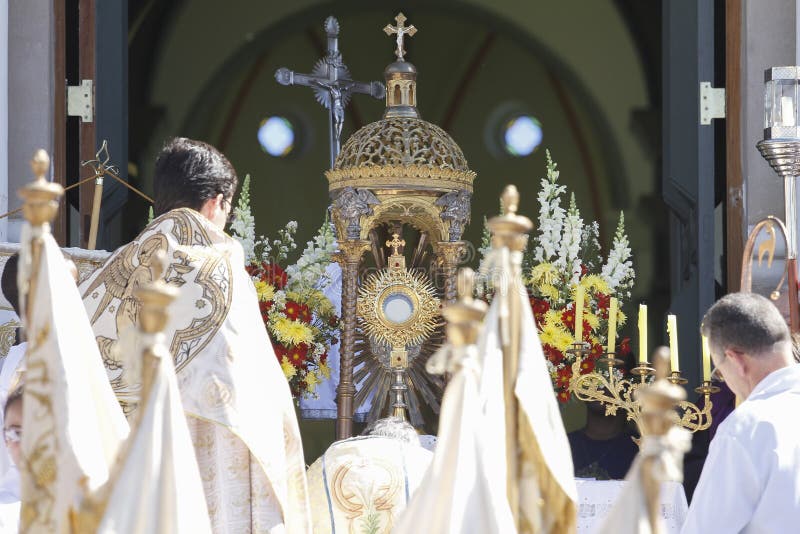 OLIVEIRA, MG / BRAZIL - 2015-06-04: Catholic celebrant blesses faithful in front of church ending Corpus Christi procession. OLIVEIRA, MG / BRAZIL - 2015-06-04: Catholic celebrant blesses faithful in front of church ending Corpus Christi procession