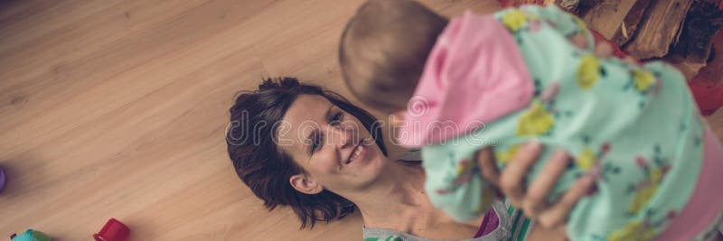 Ευρεία αναδρομική εικόνα άποψης του ευτυχούς νέου παιχνιδιού μητέρων με το bab της στοκ εικόνες Ευρεία αναδρομική εικόνα άποψης του ευτυχούς νέου παιχνιδιού μητέρων με το bab της στοκ εικόνες
