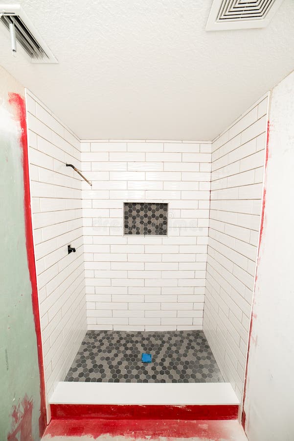 Wide angle of new shower installation in progress with large subway tiles on shower walls, Octagon tiles on floor. Narrow bathroom space. Wide angle of new shower installation in progress with large subway tiles on shower walls, Octagon tiles on floor. Narrow bathroom space.