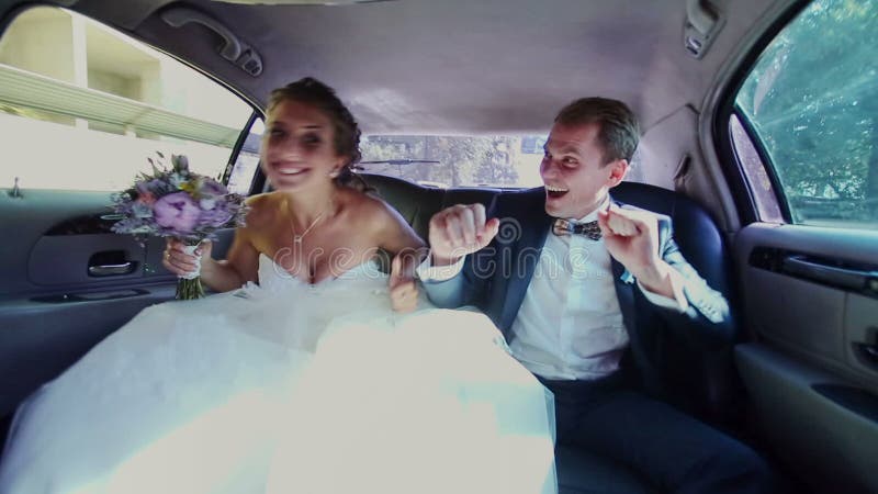 Ευτυχές Newlyweds που έχει τη διασκέδαση σε μια λιμουζίνα απόθεμα βίντεο