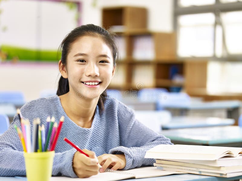 Happy asian elementary school student studying in classroom looking at camera smiling,. Happy asian elementary school student studying in classroom looking at camera smiling,