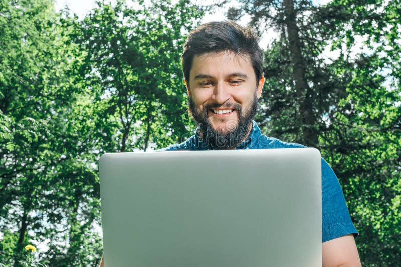 Ευτυχές εύθυμο άτομο hipster με μια συνεδρίαση lap-top υπαίθρια στο gre στοκ εικόνα με δικαίωμα ελεύθερης χρήσης Ευτυχές εύθυμο άτομο hipster με μια συνεδρίαση lap-top υπαίθρια στο gre στοκ εικόνα με δικαίωμα ελεύθερης χρήσης