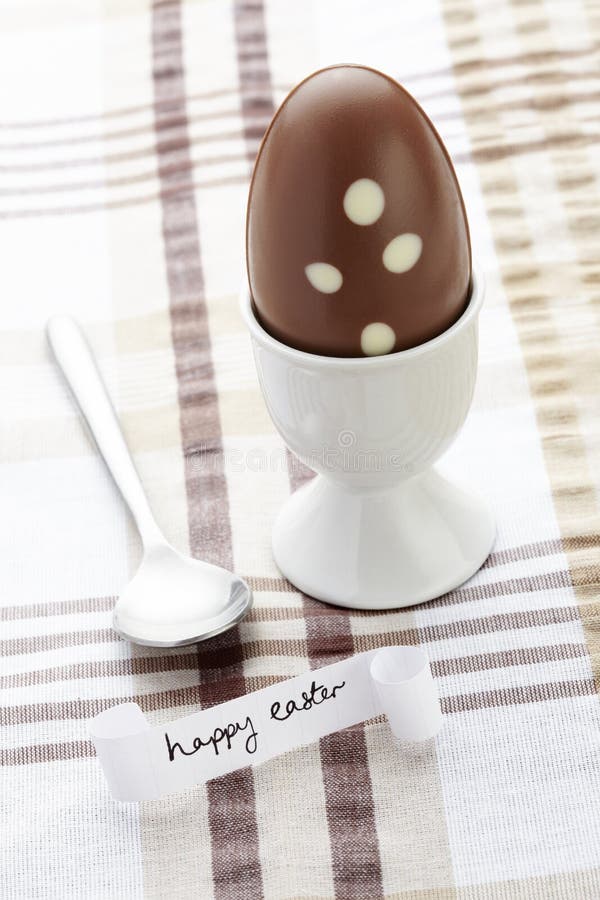 Happy easter message with chocolate egg and spoon on brown table cloth. Happy easter message with chocolate egg and spoon on brown table cloth