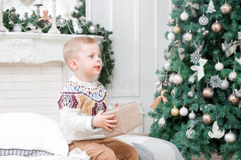 Ευτυχές μικρό παιδί το πρωί Χριστουγέννων στο σπίτι Χριστουγεννιάτικο δέντρο στο υπόβαθρο καλή χρονιά