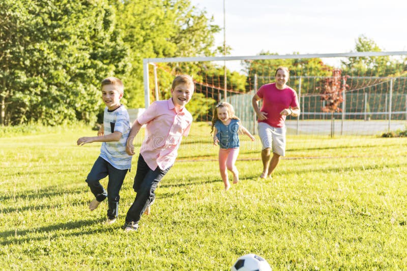 Ευτυχές ποδόσφαιρο παιχνιδιού οικογενειακού τρόπου ζωής έξω