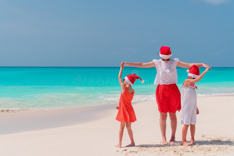 Ευτυχή μητέρα και μικρά κορίτσια στο καπέλο Santa στις θερινές διακοπές στοκ εικόνα με δικαίωμα ελεύθερης χρήσης Ευτυχή μητέρα και μικρά κορίτσια στο καπέλο Santa στις θερινές διακοπές στοκ εικόνα με δικαίωμα ελεύθερης χρήσης