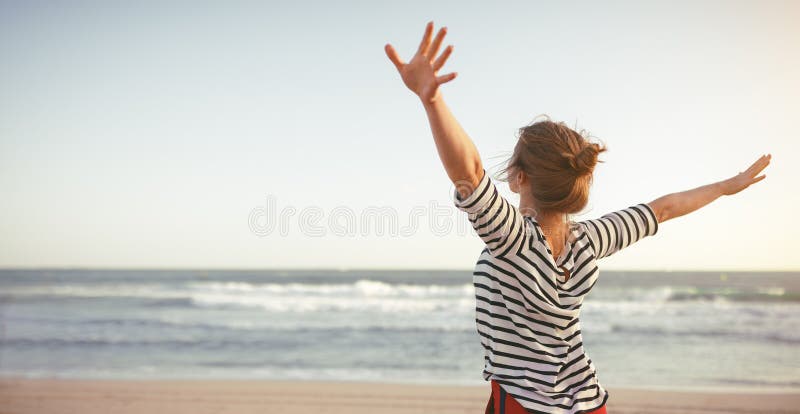 Ευτυχής γυναίκα που απολαμβάνει της ελευθερίας με τα ανοικτά χέρια στη θάλασσα