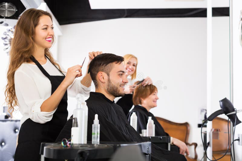 Ευτυχής κομμωτής που κάνει hairstyle στοκ φωτογραφία με δικαίωμα ελεύθερης χρήσης Ευτυχής κομμωτής που κάνει hairstyle στοκ φωτογραφία με δικαίωμα ελεύθερης χρήσης