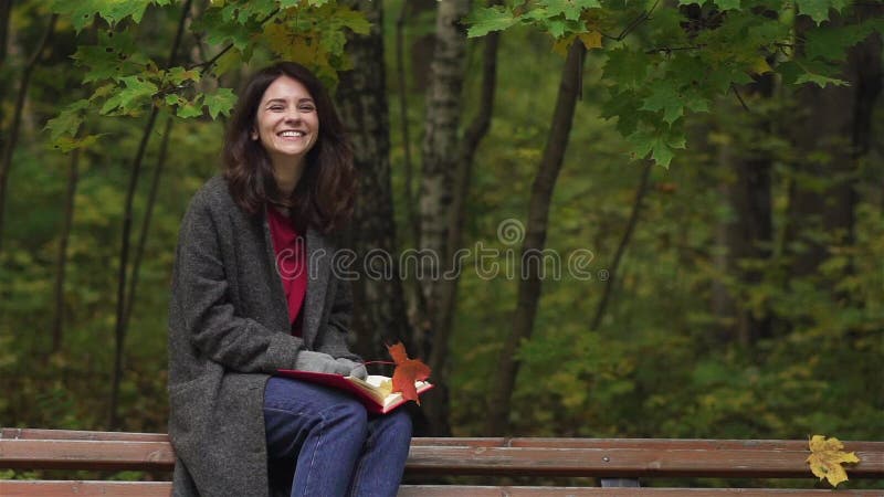 Ευτυχής νέα γυναίκα κάτω από τα μειωμένα φύλλα σε ένα πάρκο