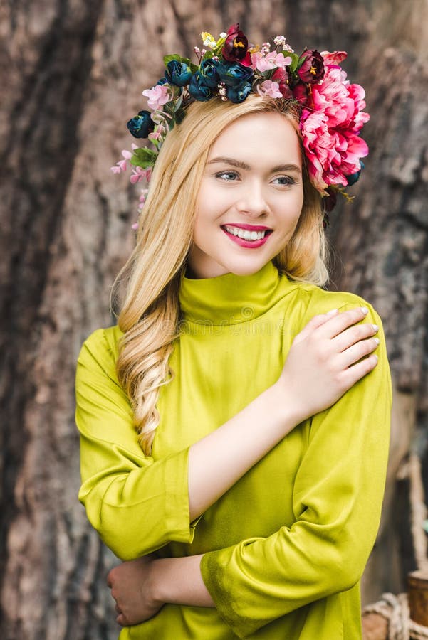 ευτυχής νέα γυναίκα με το floral στεφάνι με το θολωμένο κορμό δέντρων στοκ εικόνες ευτυχής νέα γυναίκα με το floral στεφάνι με το θολωμένο κορμό δέντρων στοκ εικόνες